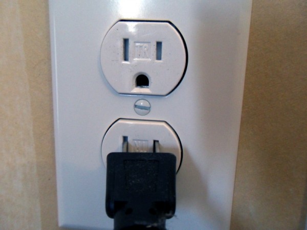 Ivory duplex receptacle with a small TR stamp on the face between the two vertical slots